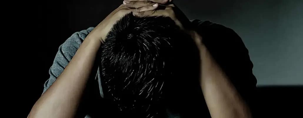 Homem com a cabeça baixa e mão entreçalada acima da cabeça com Depressão