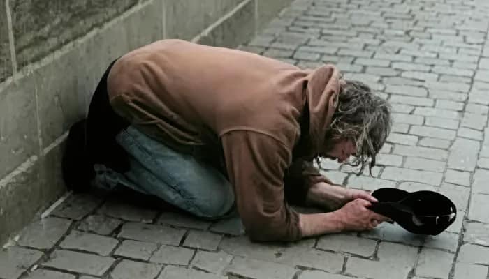 Homem com blusa marrom ajoelhado pedindo esmolas. Seja realmente piedoso.